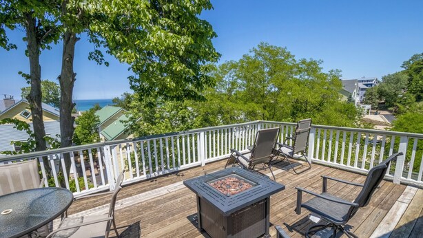 A wooden deck with a fire pit, outdoor seating, and a view of the ocean. - Massive Beachwalk Resort Home with Lake Views (Michigan City)
