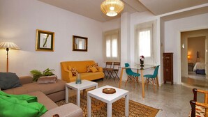 Un salon moderne comprenant un canapé, des fauteuils, une table basse et un coin repas avec des chaises et une table en verre.