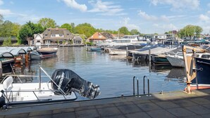 A marina with various boats docked, a house with a red roof, and a clear blue sky.