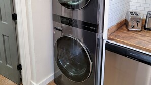 Una cocina compacta con lavadora y secadora integradas, una encimera de madera y un tostador.
