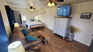 Un espacio habitable compacto con cama, sofá, televisor y mueble.
