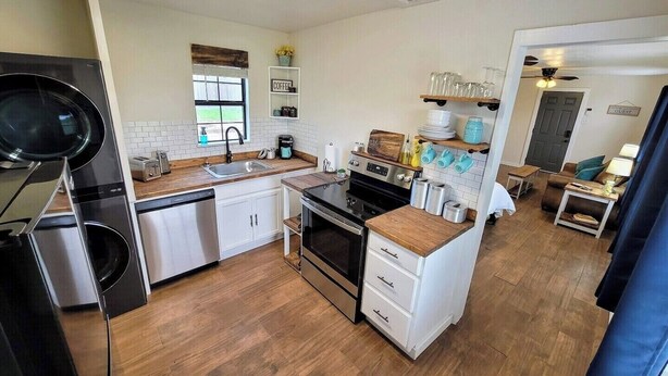 Cocina compacta equipada con lavavajillas, estufa y lavabo.  Cuenta con un pequeño comedor con mesa y sillas.