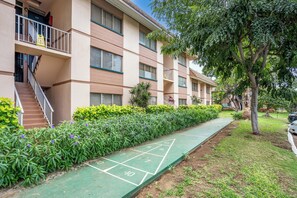 A multi-story residential building with a green shuffleboard court in the courtyard.