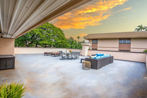 An outdoor patio with a table and chairs, a sofa, and a decorative basket.