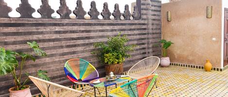 A patio with two colorful chairs, a small table, and potted plants.
