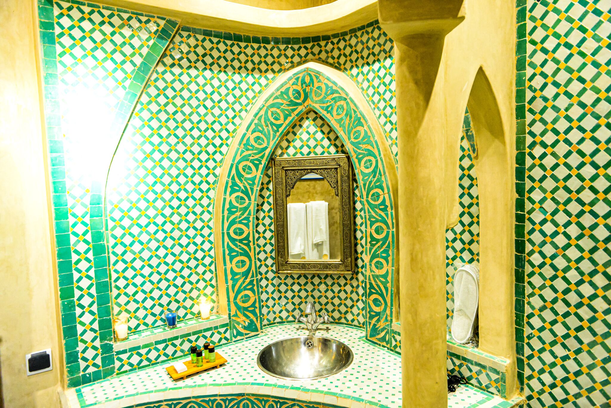 A bathroom with a sink, mirror, and tiled walls.