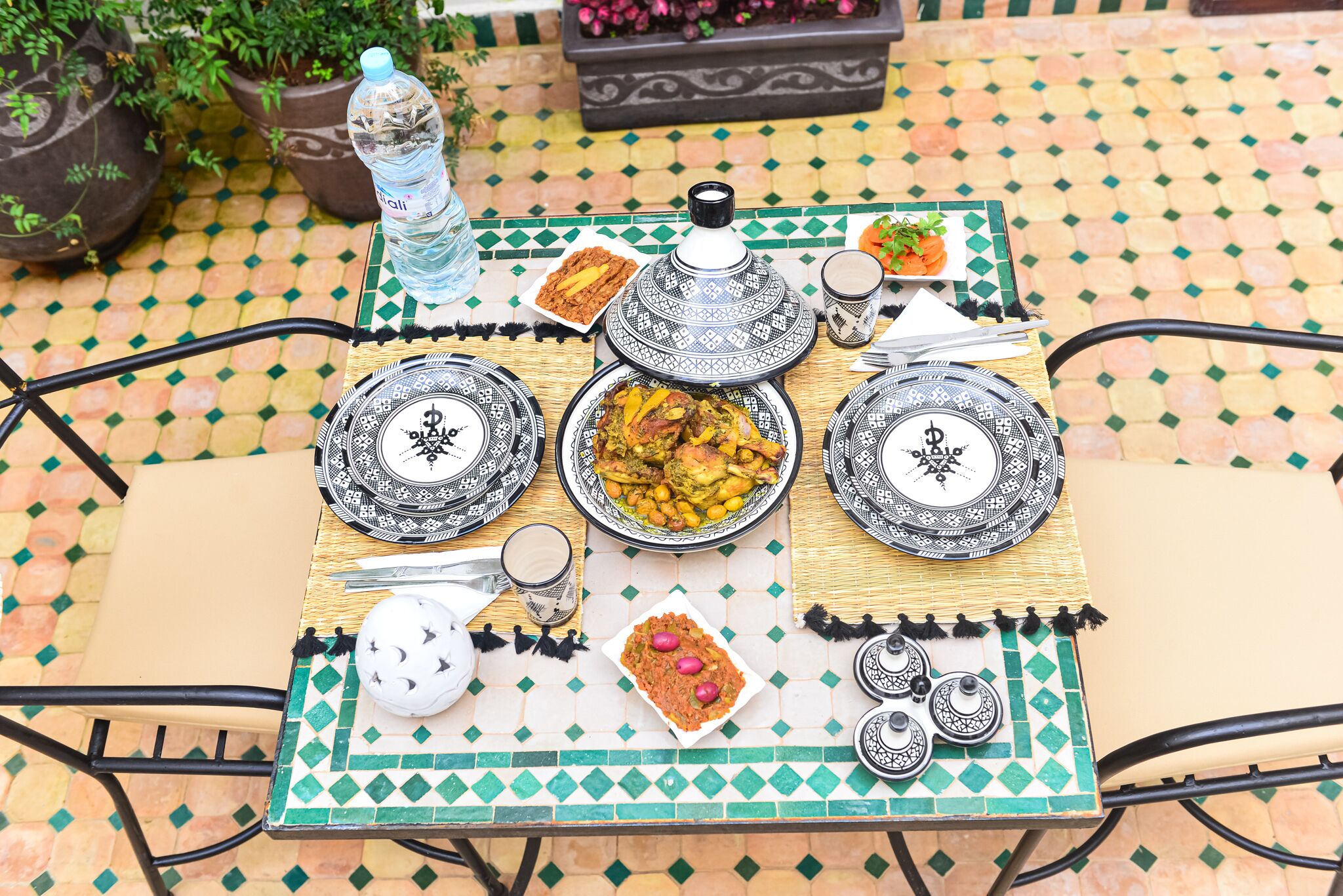 A table set with traditional Moroccan dishes, a water bottle, and a teapot.