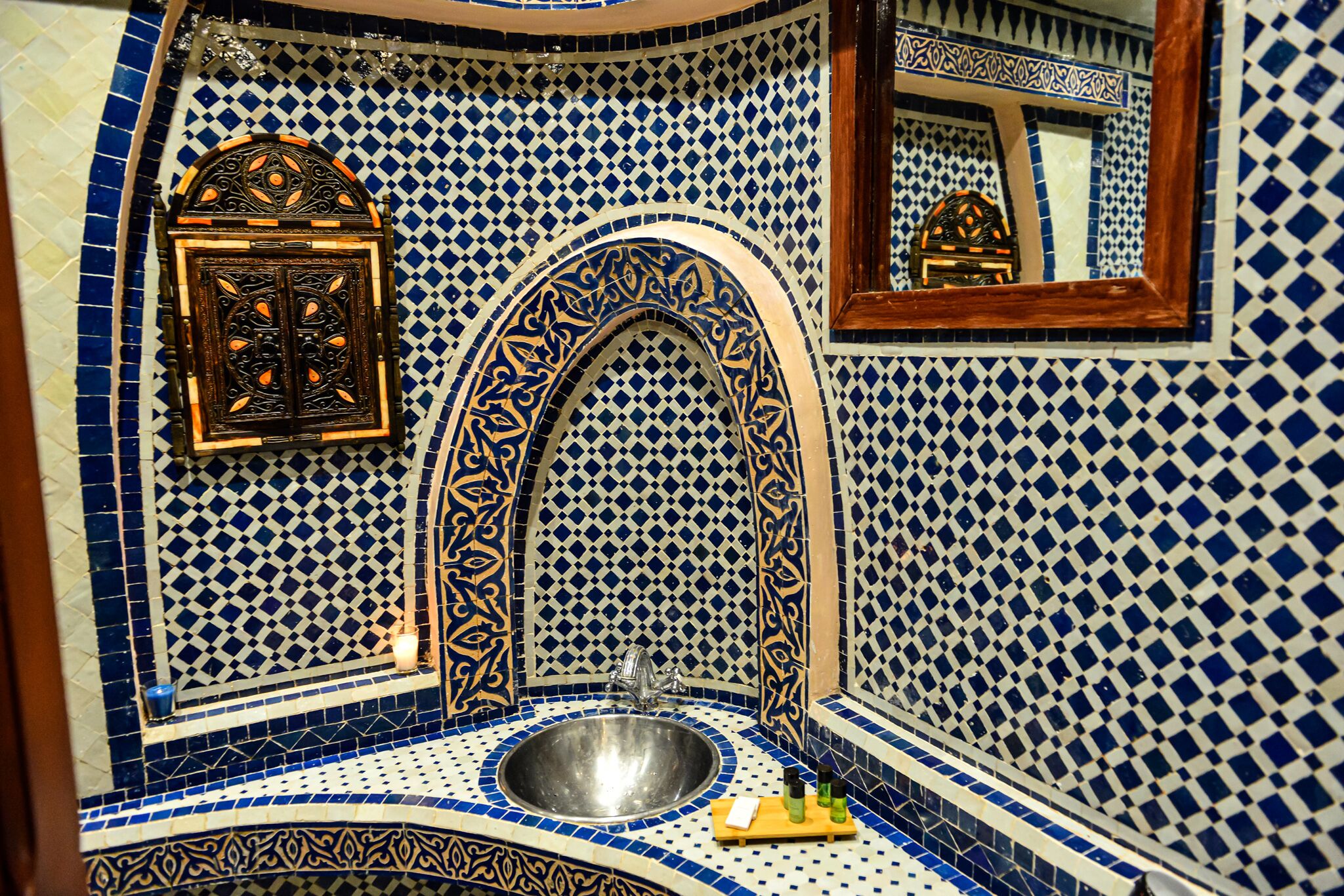 Un baño con lavamanos, espejo y azulejos decorativos.