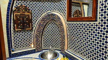 Un baño con lavamanos, espejo y azulejos decorativos.