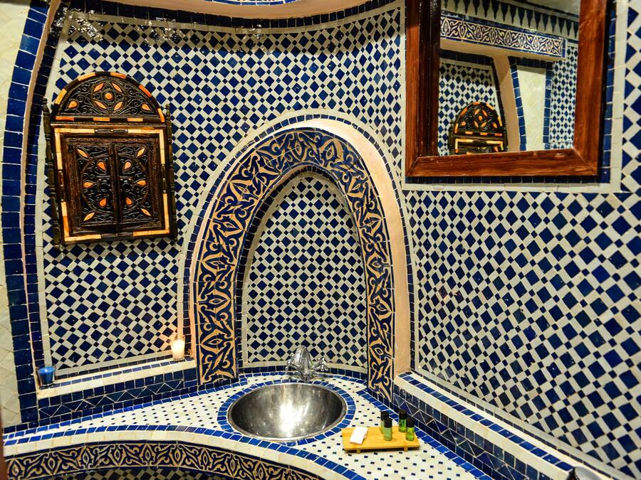 Un baño con lavamanos, espejo y azulejos decorativos.