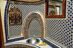 A bathroom with a sink, mirror, and decorative tiles.
