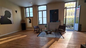 Ein geräumiges Wohnzimmer mit Holzboden, großen Fenstern und modernen Möbeln.