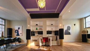 Ein modernes Interieur mit Holzboden, einer zentralen Sitzecke mit einem roten Sessel und einem Kuhfellteppich.