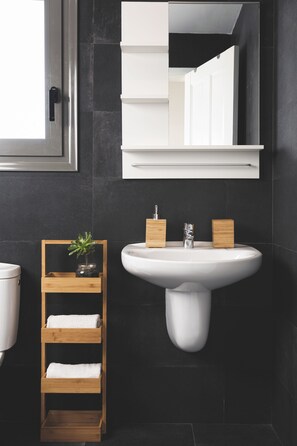 Une salle de bain moderne avec un lavabo blanc, des étagères en bois et un miroir au-dessus du lavabo.