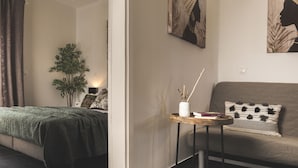 A modern hotel room with a bed, a sofa, a small table with a vase, and a plant. - Casa Maria (Zakynthos)
