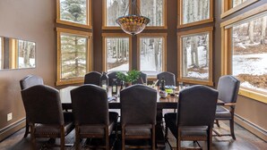 Un coin repas avec une grande table, six chaises et un lustre.