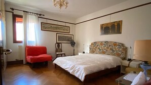 Une chambre à coucher avec un grand lit, un fauteuil rouge, une petite table et une chaise.