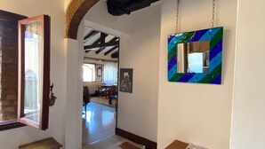 Un couloir avec un banc en bois, une table et un tableau abstrait aux couleurs vives accroché au mur.