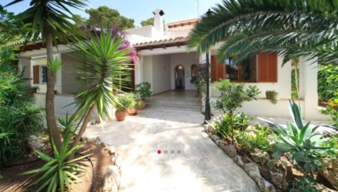 A house with a tiled roof, a stone pathway, and various plants.