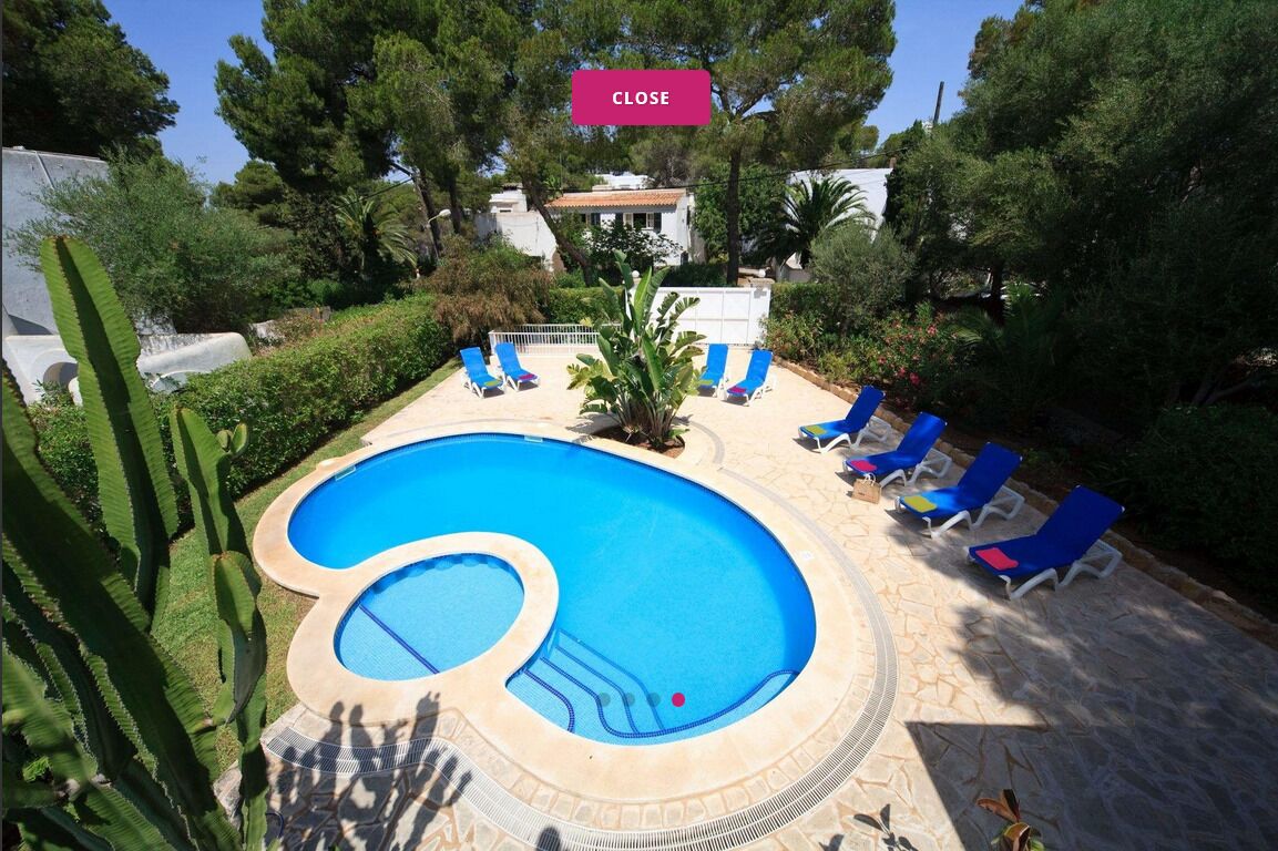 A swimming pool with blue water, surrounded by lounge chairs and a stone deck.