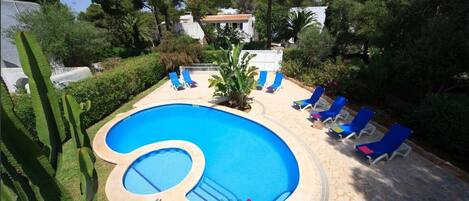 A swimming pool with blue water, surrounded by lounge chairs and a stone deck.