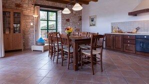 Une cuisine rustique avec une table à manger en bois, des murs en pierre et un sol carrelé.