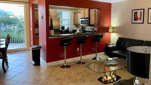 A compact living space with a kitchenette, a dining area, and a seating area with a sofa and a glass coffee table.