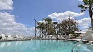 A swimming pool with clear blue water, surrounded by lounge chairs and palm trees.