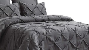 A bed with a tufted, dark grey duvet cover and matching pillows.