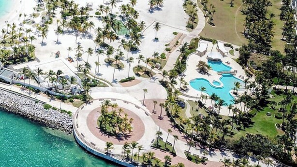 Vue aérienne d’un complexe hôtelier doté de plusieurs piscines, d’une plage et de palmiers.