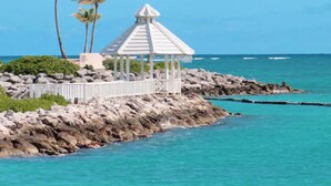 Un kiosque blanc avec un toit triangulaire, situé sur une côte rocheuse.