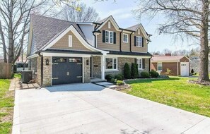 A two-story house with a garage, a driveway, and a well-maintained lawn.