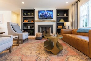 A living room with a fireplace, a television displaying a show, and a sofa.