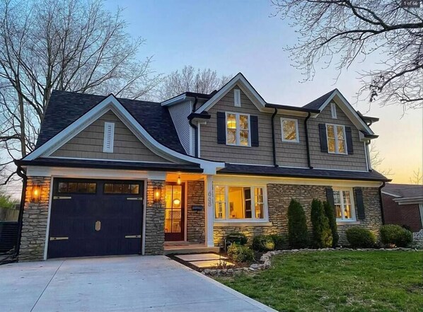 Stunning two-story home with a symmetrical facade, featuring a combination of siding and stone accents.