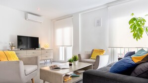 Un saló modern amb televisió plana, un sofà, una taula de centre i una planta.