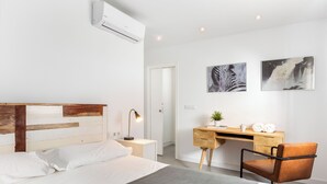 Habitació d'hotel moderna amb un llit amb capçalera de fusta, una taula de treball amb una cadira i dos quadres al mur.