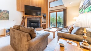 A modern living room with a fireplace, two sofas, a coffee table, and a television. - Spacious Mountain Retreat with Private Balcony Offering Slope and River Views (Keystone)