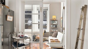 A cozy living room with a white sofa, a coffee table with a tray, a bookshelf, and a ladder leaning against the wall.
