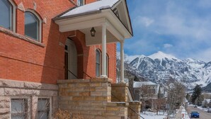 A red brick building with a stone staircase leading to a white porch.
