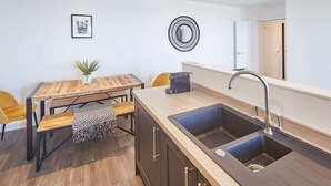 A modern kitchen with a large sink, wooden table, and a small plant. - Host & Stay | The Waves (Whitby)