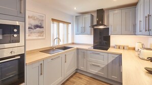 A modern kitchen with grey cabinets, a built-in oven, a sink, and a stove.