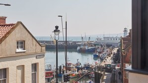 En havn med fortøjede både, et fyrtårn i baggrunden, og en bygning med teksten "Eastborough".