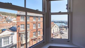 Ein Zimmer mit großem Fenster und Blick auf einen Hafen sowie Gebäude.