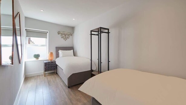 Ein Schlafzimmer mit Bett, Schrank, Nachttisch und einem Fenster mit Blick.