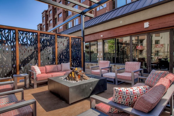 An outdoor seating area with sofas and chairs, a fire pit, and a view of a building in the background. - Village Antero Mercury SuperChair Condo: Ski-In/Out (Breckenridge)