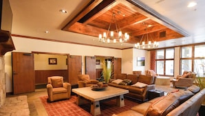 A spacious living room with leather sofas, a stone coffee table, and a wooden ceiling. - Riverbend Snowflake Run Condo: At Snowflake Lift (Breckenridge)