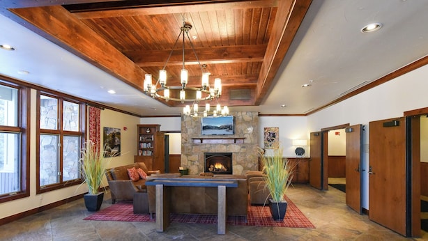 A spacious living area with a stone fireplace, wooden ceiling, and a large chandelier. - Riverbend Snowflake Run Condo: At Snowflake Lift (Breckenridge)