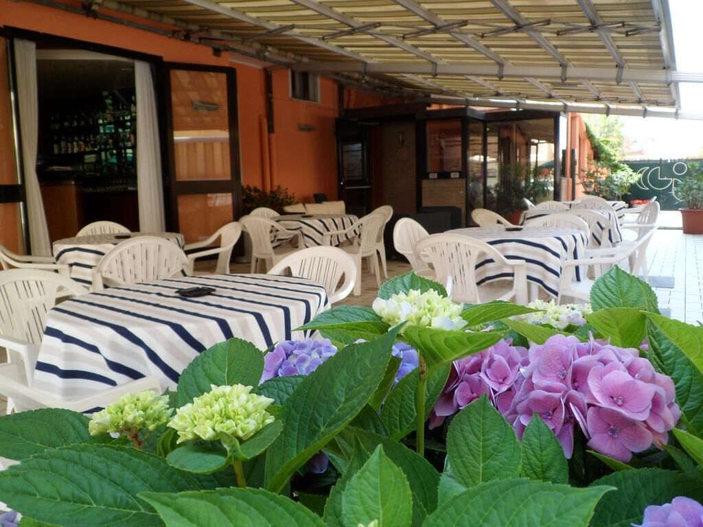 Un espace extérieur aménagé avec des chaises et des tables en plastique blanc, dont certaines sont recouvertes de nappes à rayures.