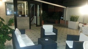 An outdoor seating area with wicker furniture and potted plants. - Hotel Europeo (Chioggia)