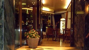 A lobby with a marble floor, a reception desk, and a bar area with chairs and a counter. - Hotel Europeo (Chioggia)